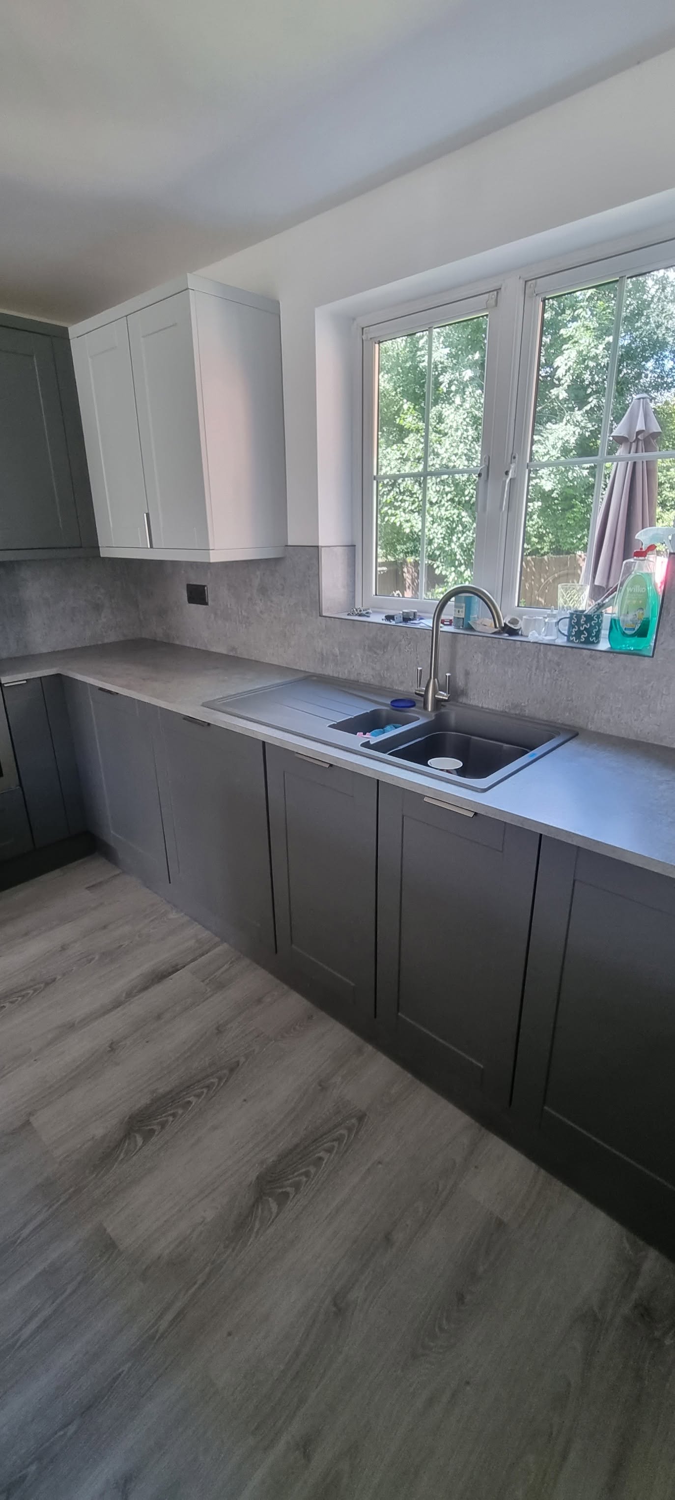 Two-tone grey shaker kitchen with dark base units, light wall units and grey composite double sink by LMB Joinery.