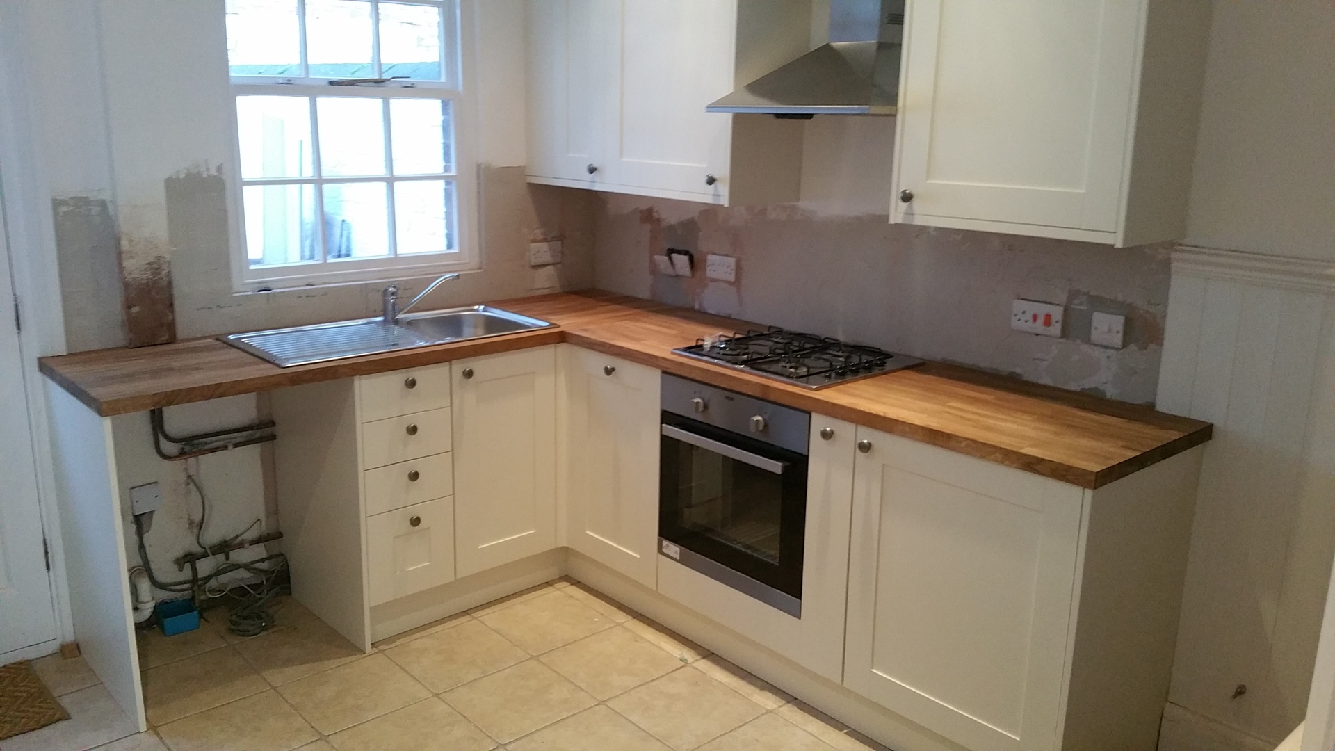 Shaker kitchen mid-installation with solid oak worktops fitted around hob and sink by LMB Joinery.