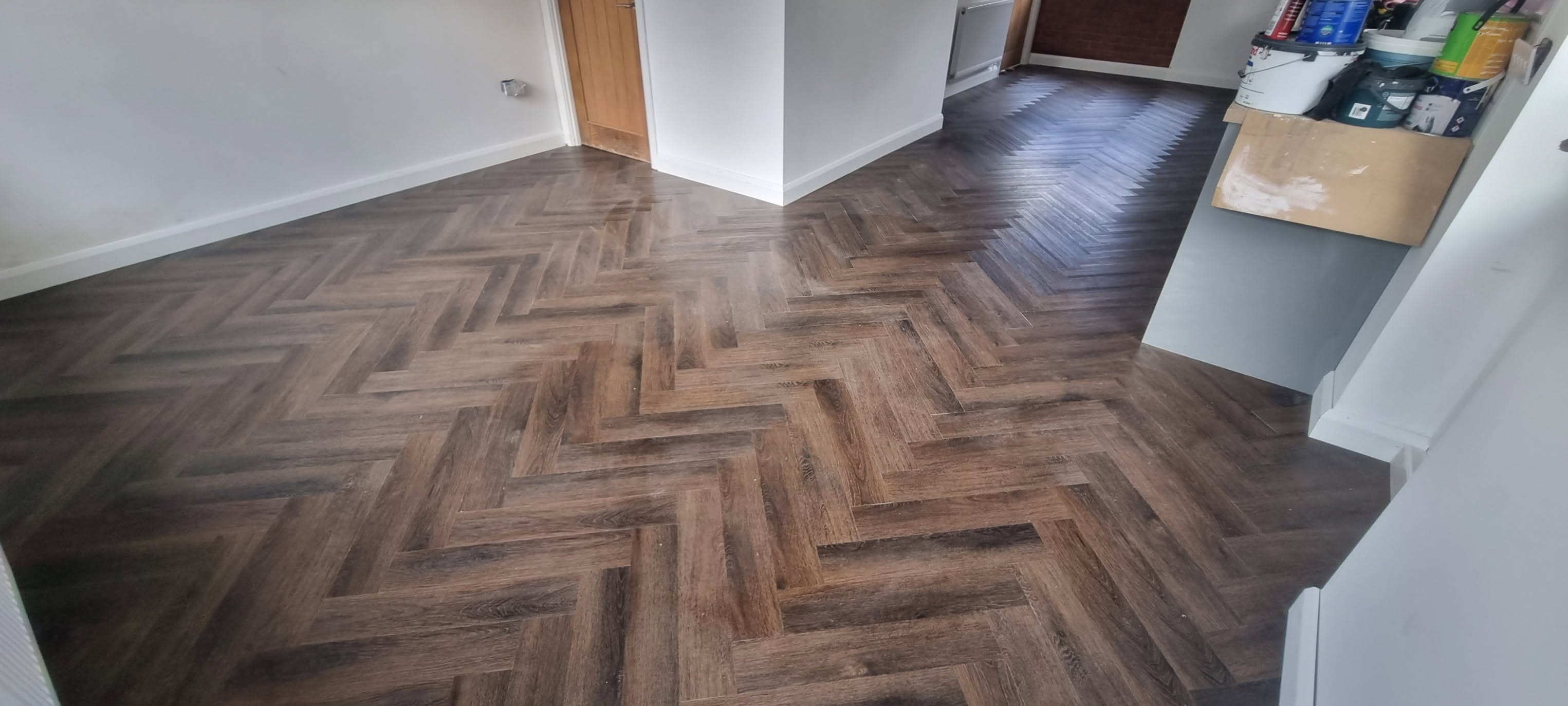 Dark oak herringbone luxury vinyl flooring laid through open-plan living space by LMB Joinery.